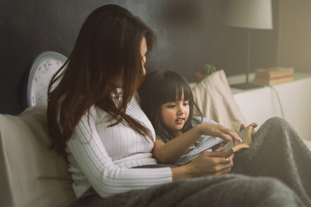 Mother and daughter reading a book in bed